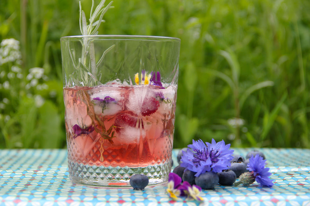 Green Vitality glas met EM drink buiten op tafel met kruiden en bloemen